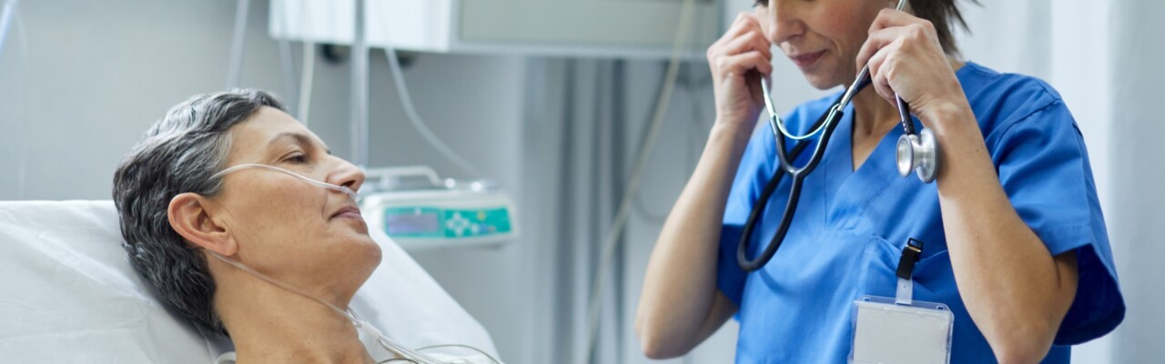 An ICU nurse is putting the stethoscope on her ears to examine a patient.