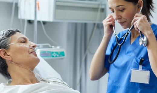 An ICU nurse is putting the stethoscope on her ears to examine a patient.